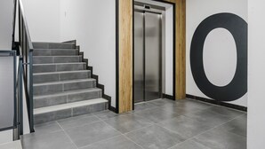 Un interior moderno con una escalera, un ascensor y un gran diseño circular negro en la pared.