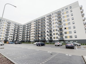 A multi-story residential building with balconies, a parking area, and a street lamp. - Osiedle Verde Homely Apartment (Poznan)
