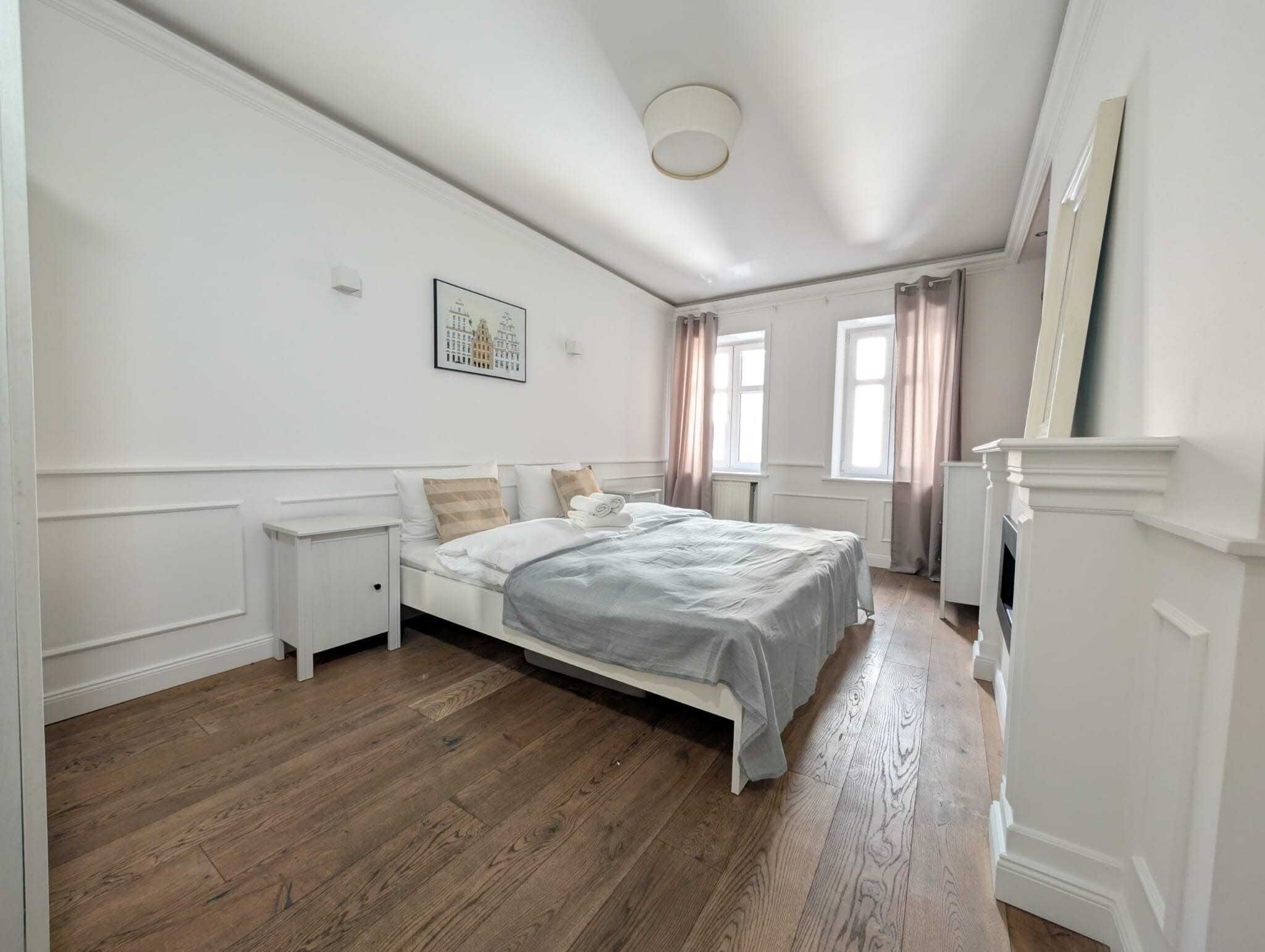 Une chambre à coucher avec un lit, des tables de chevet, un radiateur et une cheminée.