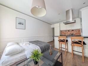 A compact, modern apartment with a kitchenette, a dining area, and a bedroom.