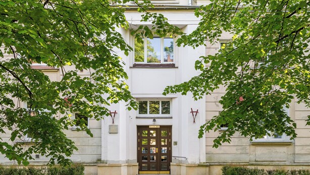 A building with a central entrance, flanked by symmetrical windows and a door with glass panels.