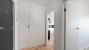 A hallway with a wooden floor, white walls, and a closed door on the right.