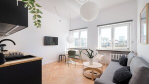 A modern living room with a grey sofa, a round coffee table, and a TV mounted on the wall.