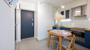 Una cucina moderna con zona pranzo, con un tavolo in legno, sedie e un vaso con pampa.