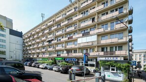 Un condominio a più piani con balconi, un'area parcheggio e diversi negozi, tra cui un salone di parrucchiere.