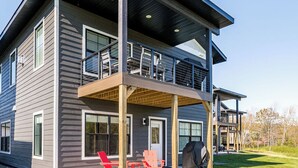 A modern two-story house with a covered patio, large windows, and a visible outdoor seating area. - RiverWest Stones Throw Chalet - Hot Tub -  Sauna - River View - Sauna - Dogs (Duluth)