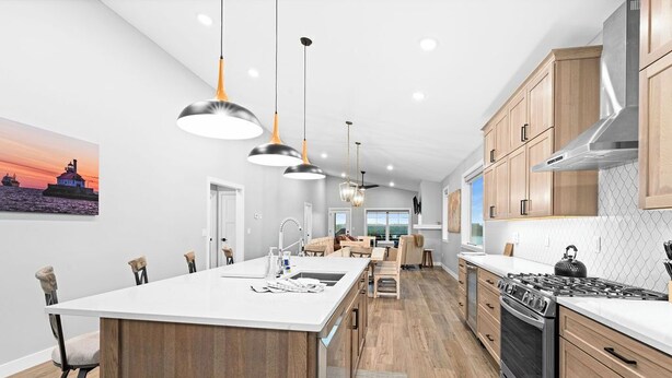 A modern kitchen with a central island, wooden cabinets, and pendant lighting. - RiverWest Stones Throw Chalet - Hot Tub -  Sauna - River View - Sauna - Dogs (Duluth)