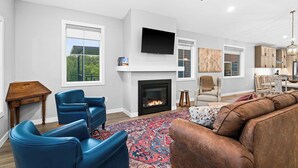 A modern living room with a fireplace, blue leather chairs, a brown leather sofa, and a large rug. - RiverWest Stones Throw Chalet - Hot Tub -  Sauna - River View - Sauna - Dogs (Duluth)