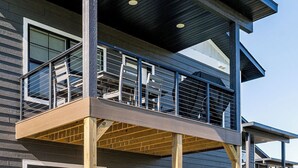 Un bâtiment moderne à deux étages, doté d’un balcon, de grandes fenêtres et d’une terrasse en bois.