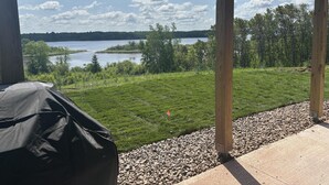 A covered outdoor area with a view of a lake and surrounding greenery.