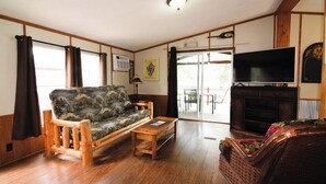 A living room with a wooden sofa, a small coffee table, a television, and a fireplace.