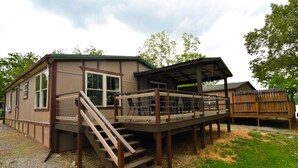 A two-story cabin with a covered deck and a staircase leading to the upper level.