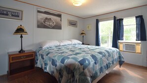 A bedroom with a bed, two bedside tables, a window with curtains, and wall decorations.