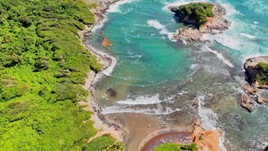 An aerial view of a coastal area with clear turquoise waters, rocky outcrops, and dense green vegetation. - Spectacular Private Ocean-Front Estate-Villa & Cottage (Wesley)