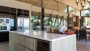 A modern kitchen with a large island, stainless steel appliances, and a view of the outdoors. - Luxe Vacay Atulya Residence | Chef & Staff | LTH-1 (Koh Sumui)
