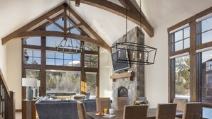 Un comedor espacioso con chimenea de piedra, ventanas amplias y un techo alto con vigas a la vista.