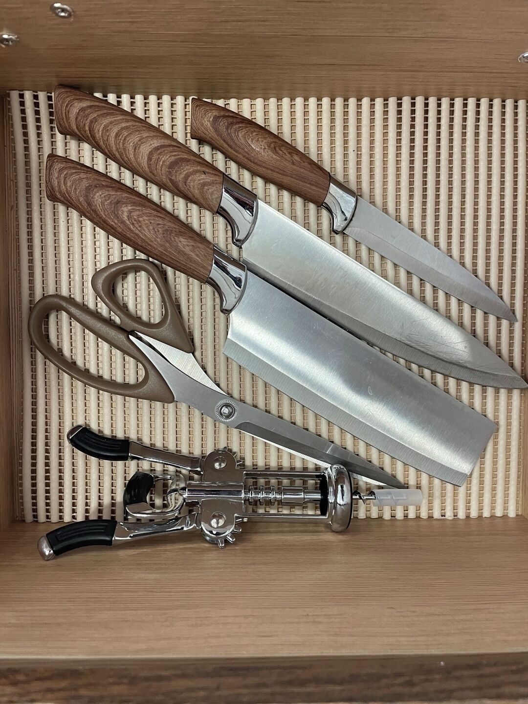 Eine Schublade mit verschiedenen Küchenutensilien, darunter Schere, Messer und Dosenöffner.