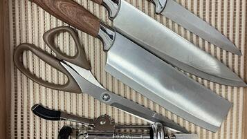 Eine Schublade mit verschiedenen Küchenutensilien, darunter Schere, Messer und Dosenöffner.