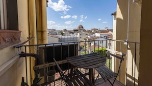 Un balcon doté d’une rambarde en métal, d’un banc en bois et offrant une vue sur un bâtiment en forme de dôme situé au loin.