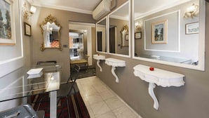 Un couloir avec une table en verre, des lavabos blancs fixés au mur et un miroir.