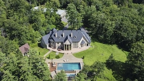 A large, two-story house with a swimming pool and a well-maintained lawn.