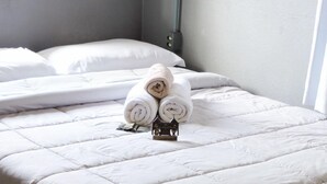A neatly made bed with a white duvet, rolled towels, and a small decorative item on the bed. - Hostel Portal Pomerode (Pomerode)