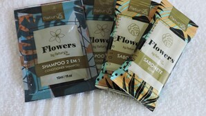 Three packages of 'Flowers by Natury’s' shampoo and soap on a white textured surface. - Hostel Portal Pomerode (Pomerode)