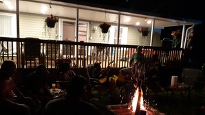 An outdoor dining area with tables and chairs, a fire pit, and hanging flower baskets. - Charming and Cozy 3-bedroom cottage w/AC, WiFi in enchanting Niagara-on-the-Lake (Niagara-on-the-Lake)