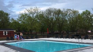 A rectangular swimming pool with a black metal fence around it, surrounded by a concrete deck. - Charming and Cozy 3-bedroom cottage w/AC, WiFi in enchanting Niagara-on-the-Lake (Niagara-on-the-Lake)