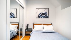 A modern bedroom with a bed, bedside tables, and abstract artwork on the walls.