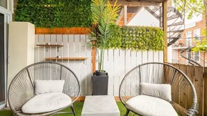 A patio with two wicker chairs, a small table, and a vertical garden wall.