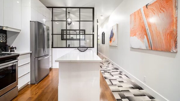 A modern kitchen with white cabinetry, stainless steel appliances, and a central island.