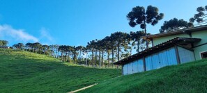Une colline sur laquelle se trouve un bâtiment doté d’un toit en tôle ondulée et d’une clôture en bois.