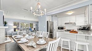 Una cocina moderna con armarios blancos, electrodomésticos de acero inoxidable y una mesa de comedor de madera para seis comensales.