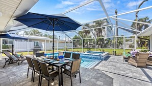 Un patio techado al aire libre con piscina, zona de estar y sombrillas.