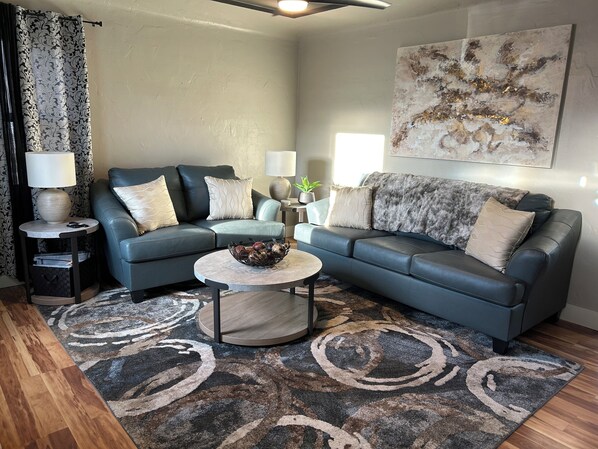 A modern living room with a grey sofa, two side tables with lamps, a coffee table, and a patterned rug. - Quaint 3-bedroom house with AC, WiFi in delightful Lewiston (Lewiston)