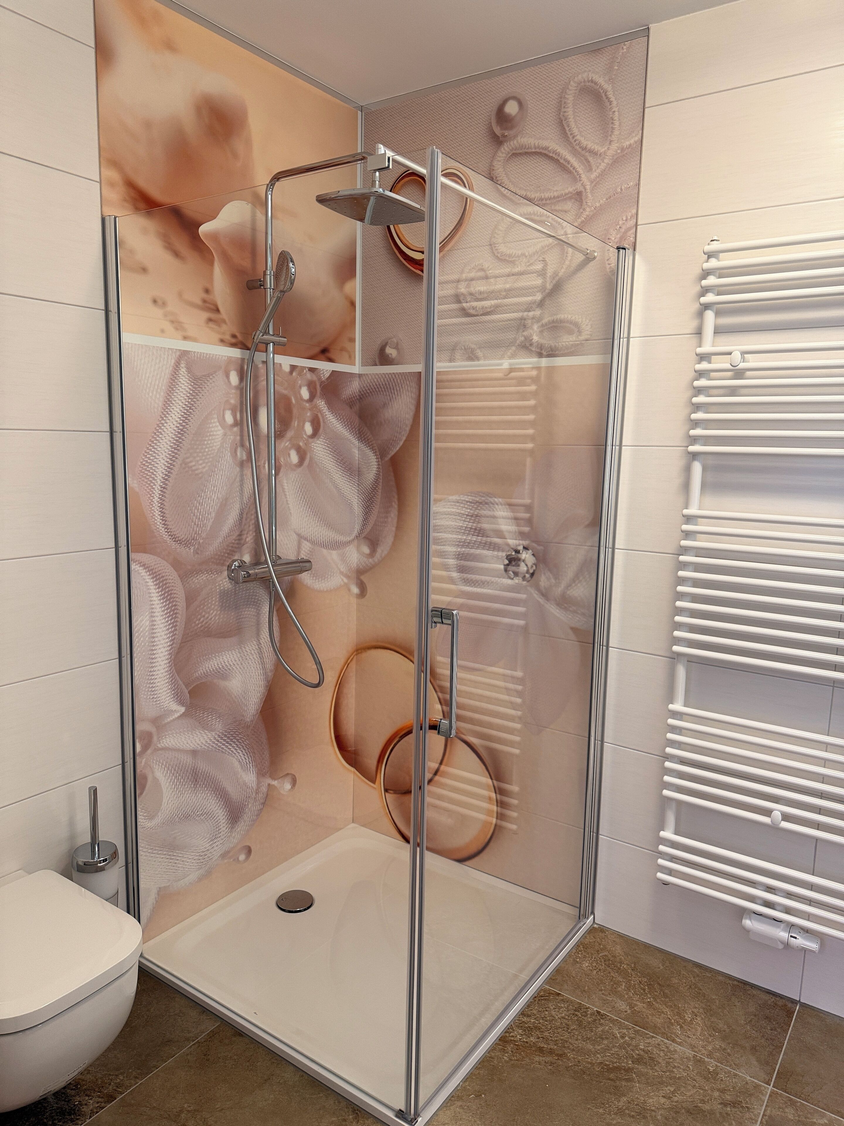 Un box de ducha moderno con puerta de vidrio, un inodoro blanco y un perchero para toallas.