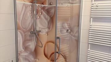 Un box de ducha moderno con puerta de vidrio, un inodoro blanco y un perchero para toallas.