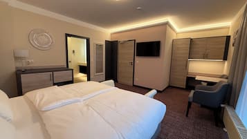 Ein Hotelzimmer mit einem großen Bett, einem Schreibtisch mit Stuhl, einem Fernseher und einem Kleiderschrank.