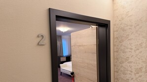 Et hotelværelse med en seng, et natbord og et vindue med gardiner.