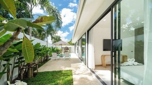 Ein modernes Hotel mit Glasfassade, Poolbereich und üppiger Bepflanzung.