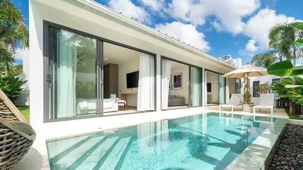 Ein modernes Haus mit Swimmingpool, großen Schiebeglastüren und Gartenmöbeln.