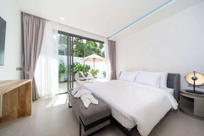 Habitación de hotel moderna con una cama grande, un escritorio de madera, un banco y vistas a zonas verdes.
