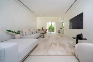 Uma sala de estar moderna com um sofá, uma mesa de centro e uma TV de tela plana na parede.