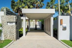 Une entrée moderne, avec un mur en pierre, une enseigne indiquant « 35/21 » et une allée couverte.