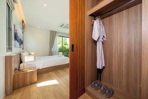 Une chambre d’hôtel comprenant un lit, une table de chevet, une lampe et une armoire en bois avec un peignoir et des chaussons.