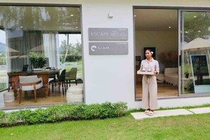 Une entrée d’hôtel moderne avec un comptoir d’accueil, une enseigne indiquant « Escape Villas », et une vue sur l’intérieur à travers les portes vitrées.