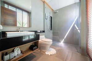 Une salle de bain moderne avec une douche à parois de verre, des toilettes blanches et un plan de toilette noir avec un lavabo.