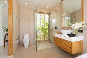Une salle de bain moderne avec une douche à parois de verre, des toilettes blanches, un meuble-lavabo en bois avec un lavabo blanc et un grand miroir.