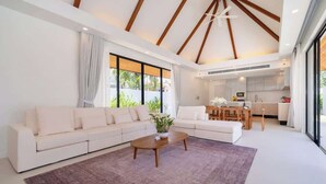 A modern living room with a sofa, a coffee table, and a view of the kitchen.